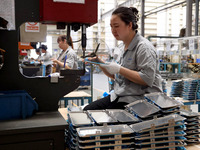 Workers are making battery pack accessories for new energy vehicles on an automated machine tool at an automated sheet metal workshop of an...