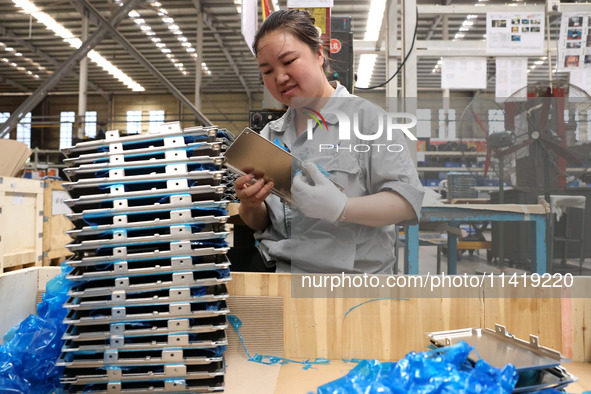 Workers are making battery pack accessories for new energy vehicles on an automated machine tool at an automated sheet metal workshop of an...