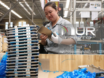 Workers are making battery pack accessories for new energy vehicles on an automated machine tool at an automated sheet metal workshop of an...