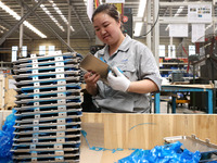 Workers are making battery pack accessories for new energy vehicles on an automated machine tool at an automated sheet metal workshop of an...