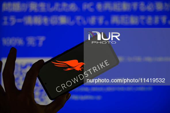 The CrowdStrike logo is being displayed on a smartphone with a Windows blue screen visible in the background in this photo illustration in B...