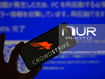 The CrowdStrike logo is being displayed on a smartphone with a Windows blue screen visible in the background in this photo illustration in B...