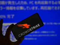 The CrowdStrike logo is being displayed on a smartphone with a Windows blue screen visible in the background in this photo illustration in B...