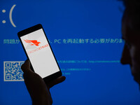 The CrowdStrike logo is being displayed on a smartphone with a Windows blue screen visible in the background in this photo illustration in B...