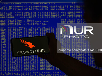 The CrowdStrike logo is being displayed on a smartphone with a Windows blue screen visible in the background in this photo illustration in B...