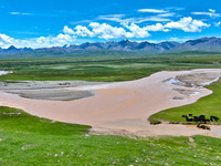 Reddish-brown water is meandering through a channel on the Tibetan Plateau in the upper reaches of Heihe River, China's second largest inlan...