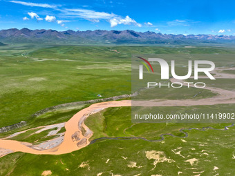 Reddish-brown water is meandering through a channel on the Tibetan Plateau in the upper reaches of Heihe River, China's second largest inlan...