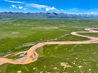 Reddish-brown water is meandering through a channel on the Tibetan Plateau in the upper reaches of Heihe River, China's second largest inlan...