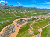 Reddish-brown water is meandering through a channel on the Tibetan Plateau in the upper reaches of Heihe River, China's second largest inlan...