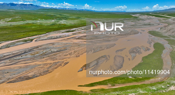 Reddish-brown water is meandering through a channel on the Tibetan Plateau in the upper reaches of Heihe River, China's second largest inlan...