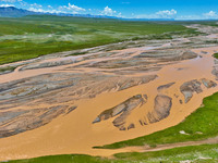 Reddish-brown water is meandering through a channel on the Tibetan Plateau in the upper reaches of Heihe River, China's second largest inlan...