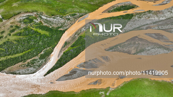 Reddish-brown water is meandering through a channel on the Tibetan Plateau in the upper reaches of Heihe River, China's second largest inlan...