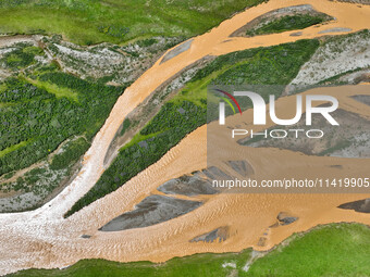 Reddish-brown water is meandering through a channel on the Tibetan Plateau in the upper reaches of Heihe River, China's second largest inlan...