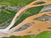 Reddish-brown water is meandering through a channel on the Tibetan Plateau in the upper reaches of Heihe River, China's second largest inlan...