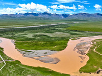 Reddish-brown water is meandering through a channel on the Tibetan Plateau in the upper reaches of Heihe River, China's second largest inlan...