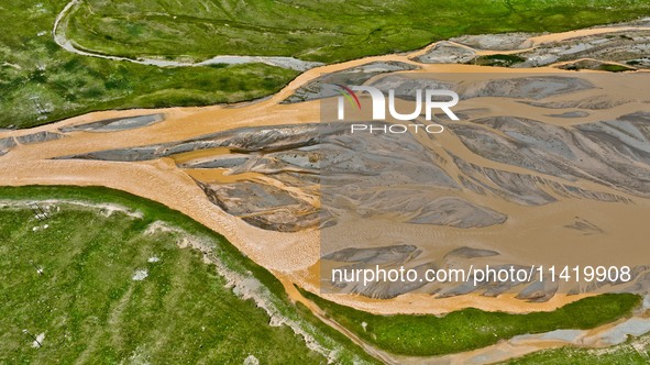 Reddish-brown water is meandering through a channel on the Tibetan Plateau in the upper reaches of Heihe River, China's second largest inlan...