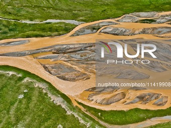 Reddish-brown water is meandering through a channel on the Tibetan Plateau in the upper reaches of Heihe River, China's second largest inlan...