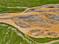 Reddish-brown water is meandering through a channel on the Tibetan Plateau in the upper reaches of Heihe River, China's second largest inlan...