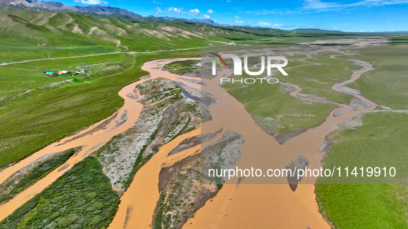 Reddish-brown water is meandering through a channel on the Tibetan Plateau in the upper reaches of Heihe River, China's second largest inlan...