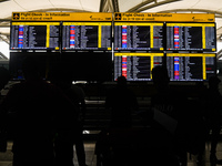 People are looking at the screens displaying flight details amid a global Microsoft outage at the Indira Gandhi International (IGI) Airport,...