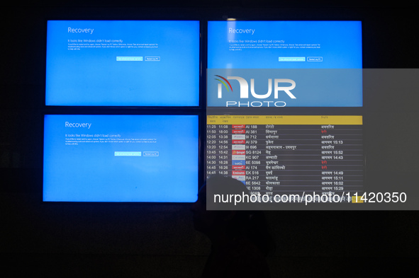 People are moving past screens displaying error messages amid a global Microsoft outage at the Indira Gandhi International (IGI) Airport, in...