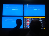 People are moving past screens displaying error messages amid a global Microsoft outage at the Indira Gandhi International (IGI) Airport, in...