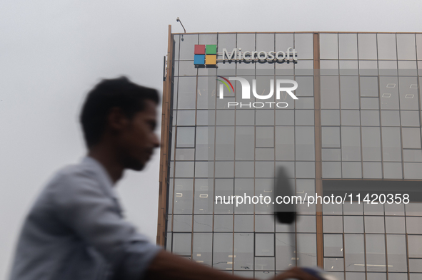 A man is riding his bike past an office building of Microsoft in Gurugram, in the outskirts of New Delhi, India, on July 19, 2024. Airlines,...