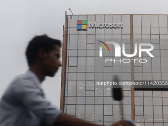 A man is riding his bike past an office building of Microsoft in Gurugram, in the outskirts of New Delhi, India, on July 19, 2024. Airlines,...