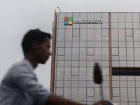 A man is riding his bike past an office building of Microsoft in Gurugram, in the outskirts of New Delhi, India, on July 19, 2024. Airlines,...