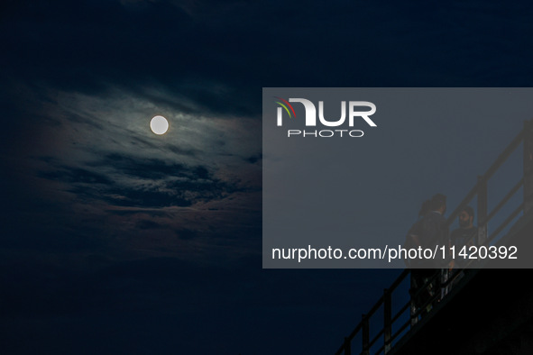 Kashmiri boys are enjoying the cool breeze on the bridge over Jhelum River as the full moon appears in Sopore, Jammu and Kashmir, India, on...