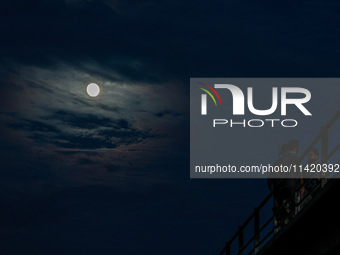 Kashmiri boys are enjoying the cool breeze on the bridge over Jhelum River as the full moon appears in Sopore, Jammu and Kashmir, India, on...