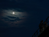 Kashmiri boys are enjoying the cool breeze on the bridge over Jhelum River as the full moon appears in Sopore, Jammu and Kashmir, India, on...