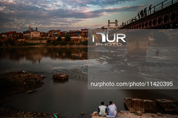 People are enjoying the cool breeze on the banks of the river Jhelum in Sopore, Jammu and Kashmir, India, on July 19, 2024. 