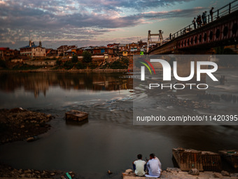 People are enjoying the cool breeze on the banks of the river Jhelum in Sopore, Jammu and Kashmir, India, on July 19, 2024. (