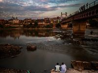 People are enjoying the cool breeze on the banks of the river Jhelum in Sopore, Jammu and Kashmir, India, on July 19, 2024. (