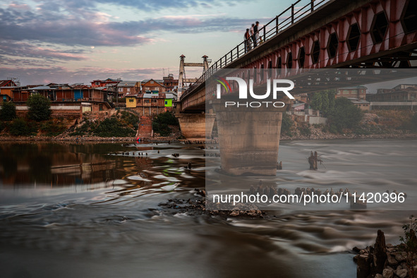 People are enjoying the cool breeze on the banks of the river Jhelum in Sopore, Jammu and Kashmir, India, on July 19, 2024. 