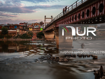 People are enjoying the cool breeze on the banks of the river Jhelum in Sopore, Jammu and Kashmir, India, on July 19, 2024. (