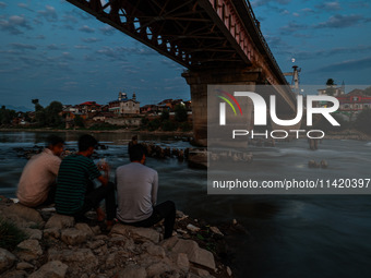 People are enjoying the cool breeze on the banks of the river Jhelum in Sopore, Jammu and Kashmir, India, on July 19, 2024. (