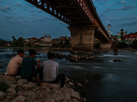 People are enjoying the cool breeze on the banks of the river Jhelum in Sopore, Jammu and Kashmir, India, on July 19, 2024. (