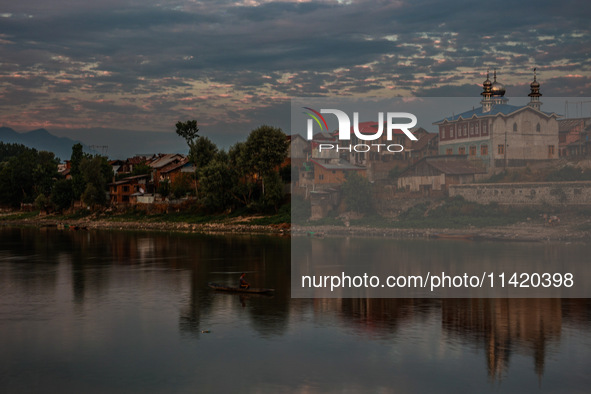 People are enjoying the cool breeze on the banks of the river Jhelum in Sopore, Jammu and Kashmir, India, on July 19, 2024. 