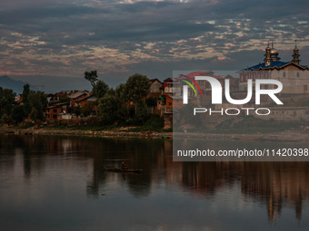 People are enjoying the cool breeze on the banks of the river Jhelum in Sopore, Jammu and Kashmir, India, on July 19, 2024. (