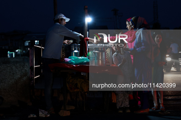 Women are purchasing snacks from a vendor in Sopore, Jammu and Kashmir, India, on July 19, 2024. 