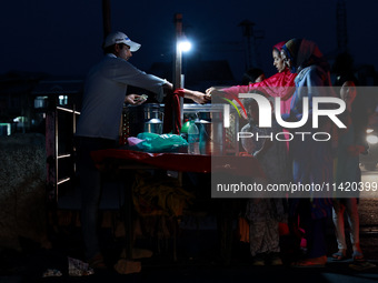 Women are purchasing snacks from a vendor in Sopore, Jammu and Kashmir, India, on July 19, 2024. (