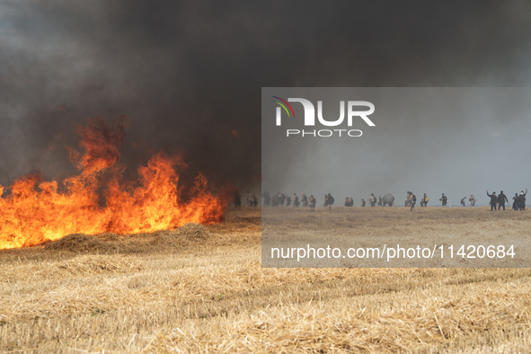 Protesters are walking past a wildfire started by a launched tear gas canister during a march as part of a rally against the construction of...