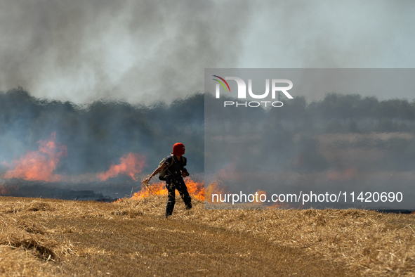 A protester is walking towards a wildfire started by a launched tear gas canister during a march as part of a rally against the construction...