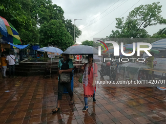 People are arriving in rain showers in Kolkata, India, on July 19, 2024. (