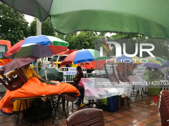 A shopkeeper is covering plastics and coloring umbrellas in rain showers in Kolkata, India, on July 19, 2024. (