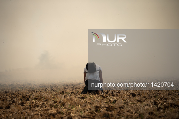 A protester is sitting in front of a wildfire started by a launched tear gas canister during a march as part of a rally against the construc...