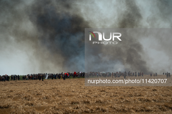 Protesters are walking past a wildfire started by a launched tear gas canister during a march as part of a rally against the construction of...