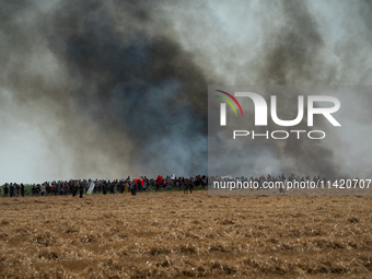 Protesters are walking past a wildfire started by a launched tear gas canister during a march as part of a rally against the construction of...